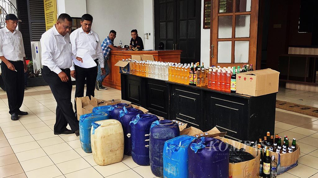 Sejumlah penyidik sedang menghitung jumlah botol dan galon berisi minuman keras oplosan yang disita dalam razia oleh jajaran Kepolisian Resor Kota Besar Bandung di Bandung, Senin (9/4/2018). Minuman keras jenis ini sehari sebelumnya telah menyebabkan kematian 26 orang di Kota dan Kabupaten Bandung.