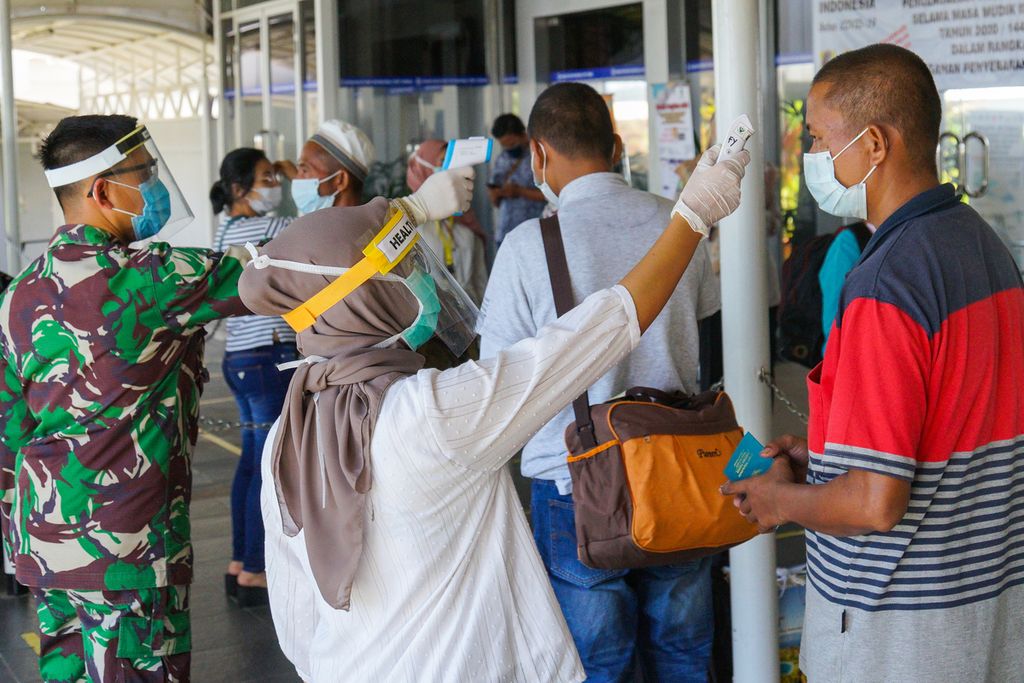 Petugas kesehatan dan anggota TNI mengukur suhu tubuh para pekerja migran Indonesia di Pelabuhan Internasional Batam Centre, Kota Batam, Kepulauan Riau, Kamis (21/5/2020).