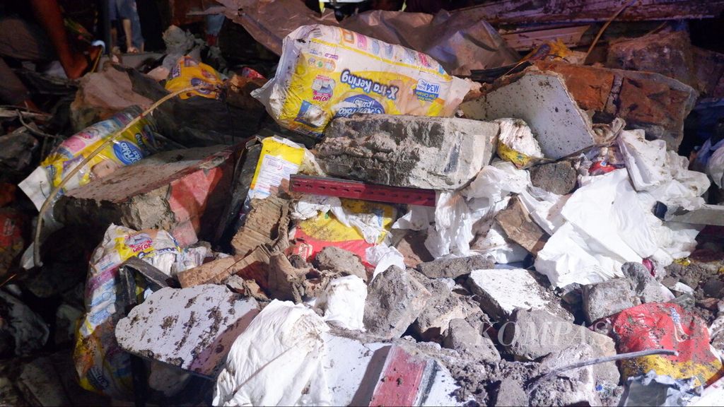Barang dagangan berserakan di antara reruntuhan bangunan rumah toko tiga lantai Alfamart di Kecamatan Gambut, Kabupaten Banjar, Kalimantan Selatan, Senin (18/4/2022) malam. 