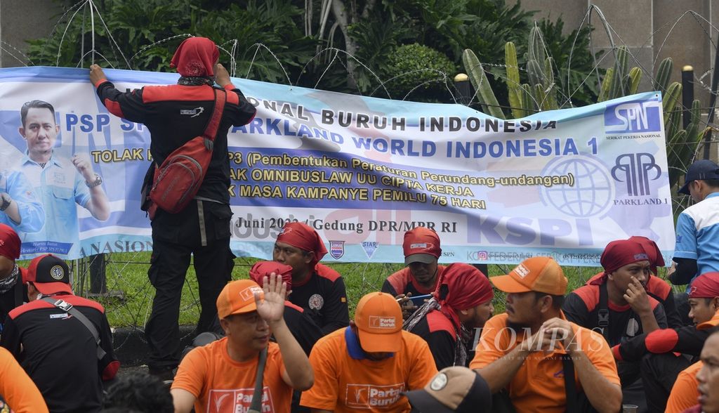 Massa buruh dari berbagai serikat pekerja berunjuk rasa di depan Gedung DPR/MPR, Jakarta, Rabu (15/6/2022). Dalam aksi yang diikuti ribuan buruh tersebut mereka kembali menyerukan penolakan atas revisi UU Pembentukan Peraturan Perundang-undangan (UU P3) dan penolakan UU Cipta Kerja. Para buruh juga menyerukan akan melakukan mogok kerja nasional jika DPR tidak mencabut revisi UU P3. KOMPAS/RADITYA HELABUMI 15-06-2022