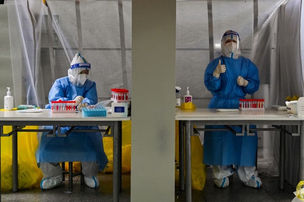 Petugas kesehatan dengan memakai alat pelindung diri menunggu untuk mengambil sampel usap warga di tengah penguncian wilayah guna mencegah persebaran virus Covid-19 di Distrik Xuhui, Shanghai, China, 29 Mei 2022.