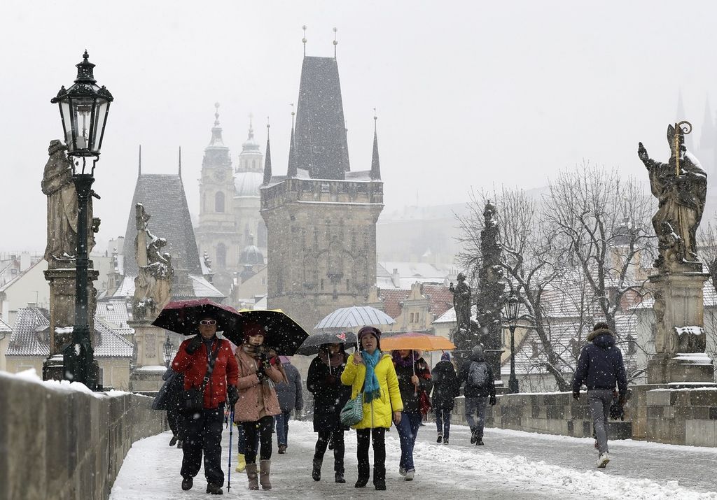 Para turis melintasi Jembatan Charles Bridge saat salju turun di Praha, Ceko, Selasa (6/3). Ceko akan memulai tugas keketuaan UE pada Juli mendatang.