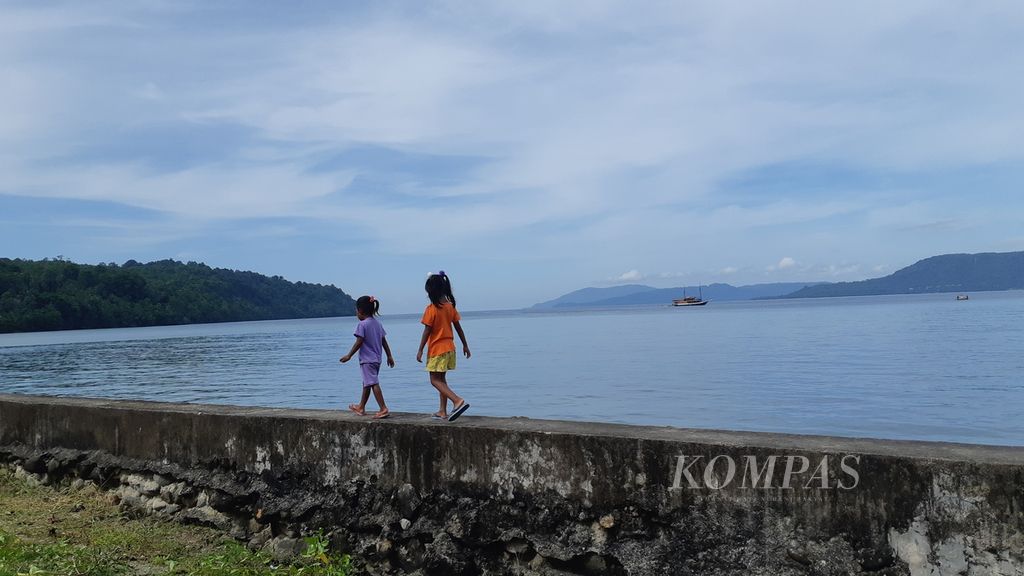 Dua bocah berjalan di atas talud di pesisir Desa Haruku, Pulau Haruku, Kabupaten Maluku Tengah, Maluku, November 2020.