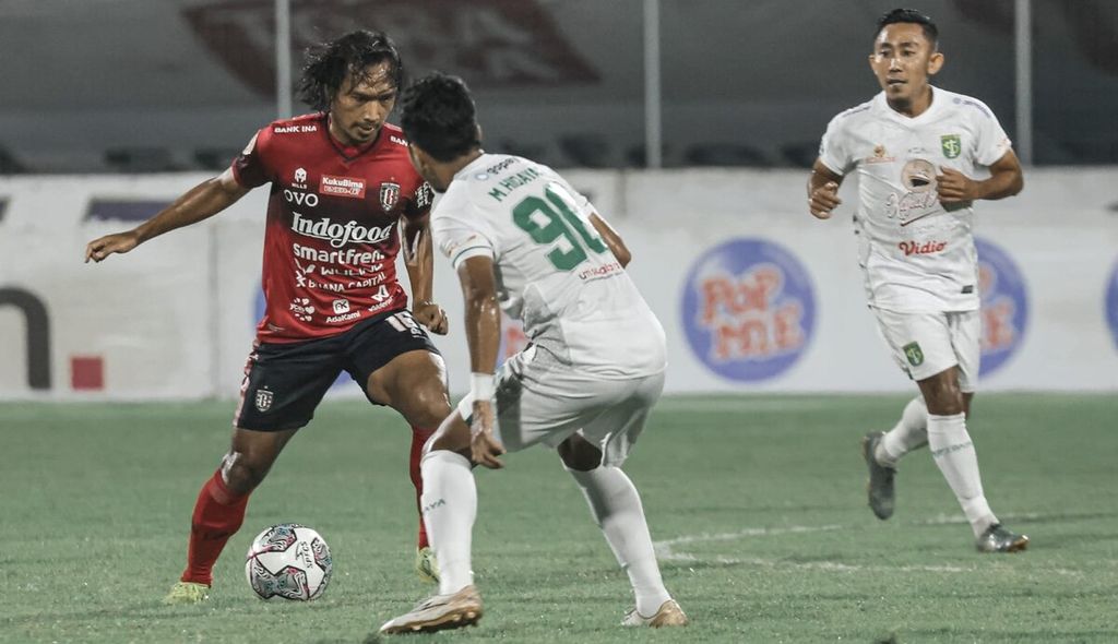 Pemain Bali United, Hariono (kiri), berhadapan dengan pemain Persebaya Surabaya, Muhammad Hidayat (kanan), pada laga pekan ke-33 BRI Liga 1 2021/2022 di Stadion I Gusti Ngurah Rai, Kota Denpasar, Jumat (25/3/2022).