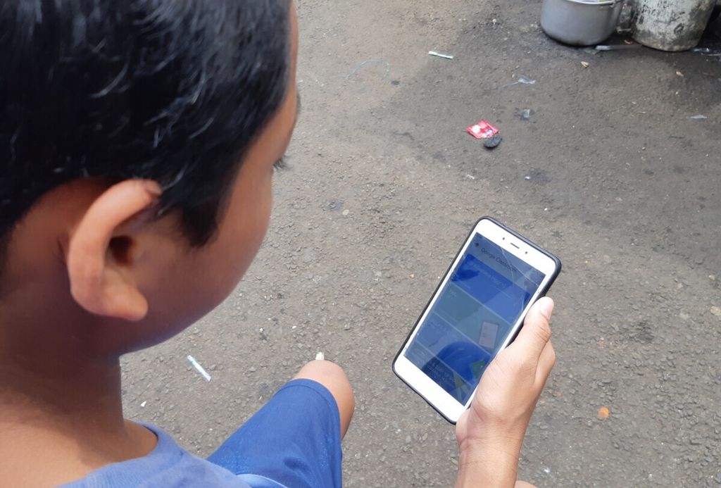 Zidan (13) mengakses tugas sekolah dari ponselnya saat sedang di rumahnya di RW 008 Petojo Utara, Gambir, Jakarta Pusat, Kamis (26/11/2020). Dia memanfaatkan akses internet gratis JakWifi dari Pemerintah Provinsi DKI Jakarta.