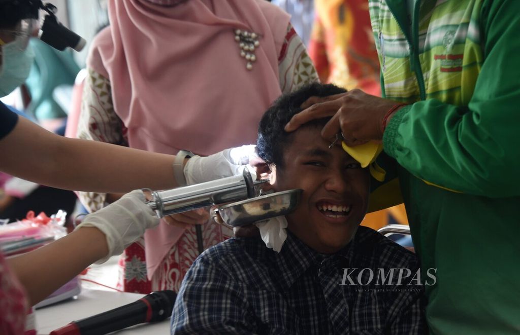 Petugas medis membersihkan kotoran telinga siswa SLB B Karya Mulia saat acara "Peduli Pendengaran untuk Semua", Surabaya, Jawa Timur, Rabu (24/2/2021).