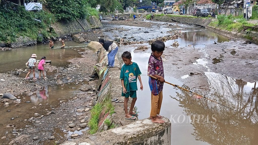 Seorang anak sedang memancing ikan di saluran irigasi Sungai Kalibaru, Sabtu (6/4/2024). Salah satu pintu Bendung Katulampa jebol pada Jumat (5/4/2024) sehingga menyebabkan Sungai Kalibaru surut.