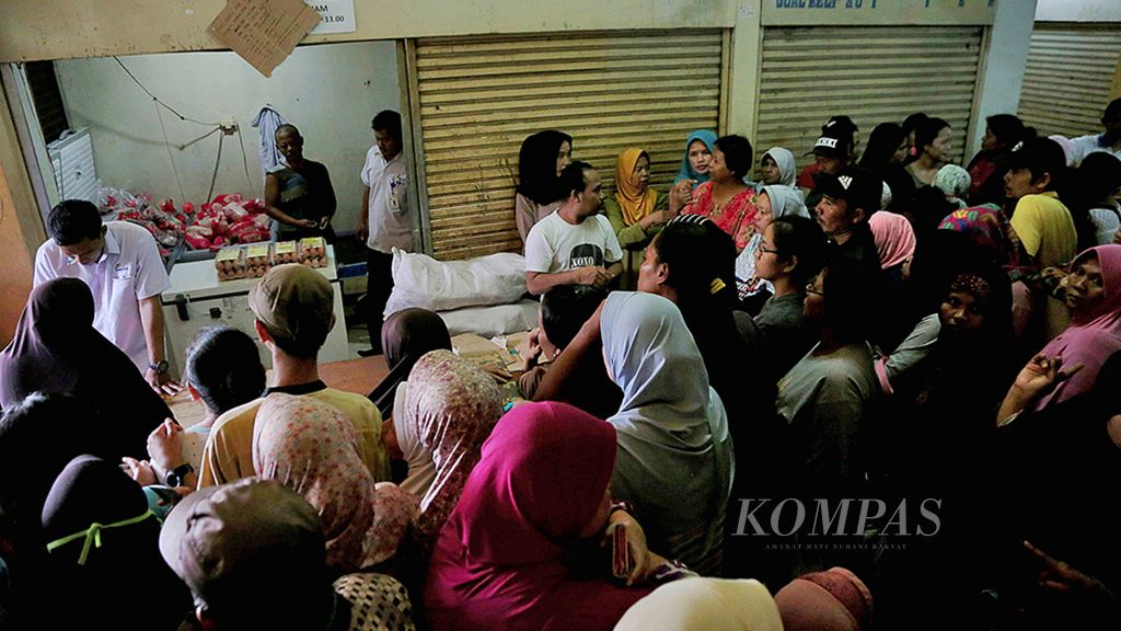 Warga menunggu dimulainya penjualan bahan pokok murah dengan menggunakan Kartu Jakarta Pintar (KJP) yang digelar oleh PD. Pasar Jaya di Pasar Kebayoran Lama, Jakarta Selatan, Rabu (21/6). 
