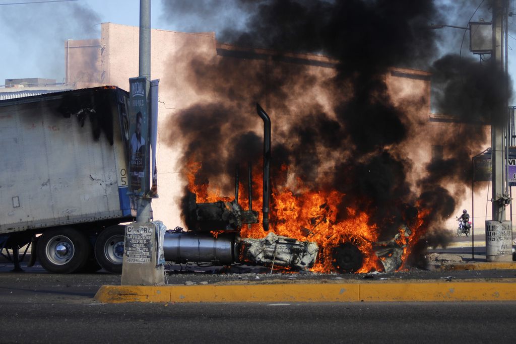 Beberapa kendaraan angkut rusak berat dan salah satunya terbakar di sebuah jalan di kota Culiacan, Sinaloa, 5 Januari 2023. Kekerasan bersenjata terjadi tidak lama setelah pemimpin anyar kartel Sinaloa, Ovidio Guzman Lopez, yang juga putra bos besar kartel Sinaloa, Joaquin Guzman Lopez, ditangkap aparat berwenang Meksiko.