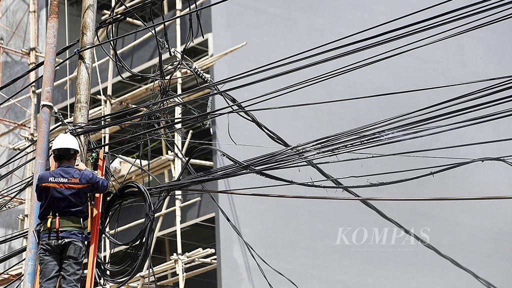 Petugas PLN  memutus jaringan kabel yang rusak karena terbakar di pinggir Jalan Ciledug, Jakarta Selatan, Selasa (2/1). Kebakaran jaringan kabel tersebut menjadi perhatian warga dan pengguna jalan sehingga menimbulkan kemacetan lalu lintas.
