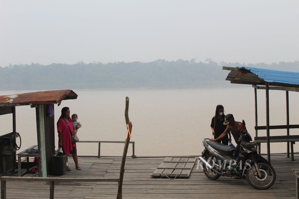 Warga Desa Simpur menggunakan kapal feri kayu untuk menyeberangi Sungai Kahayan di Kabupaten Pulang Pisau, Kalimantan Tengah, Selasa (3/10/2023). Mereka masih beraktivitas di tengah kepulan asap dari kebakaran hutan dan lahan di sekitarnya.