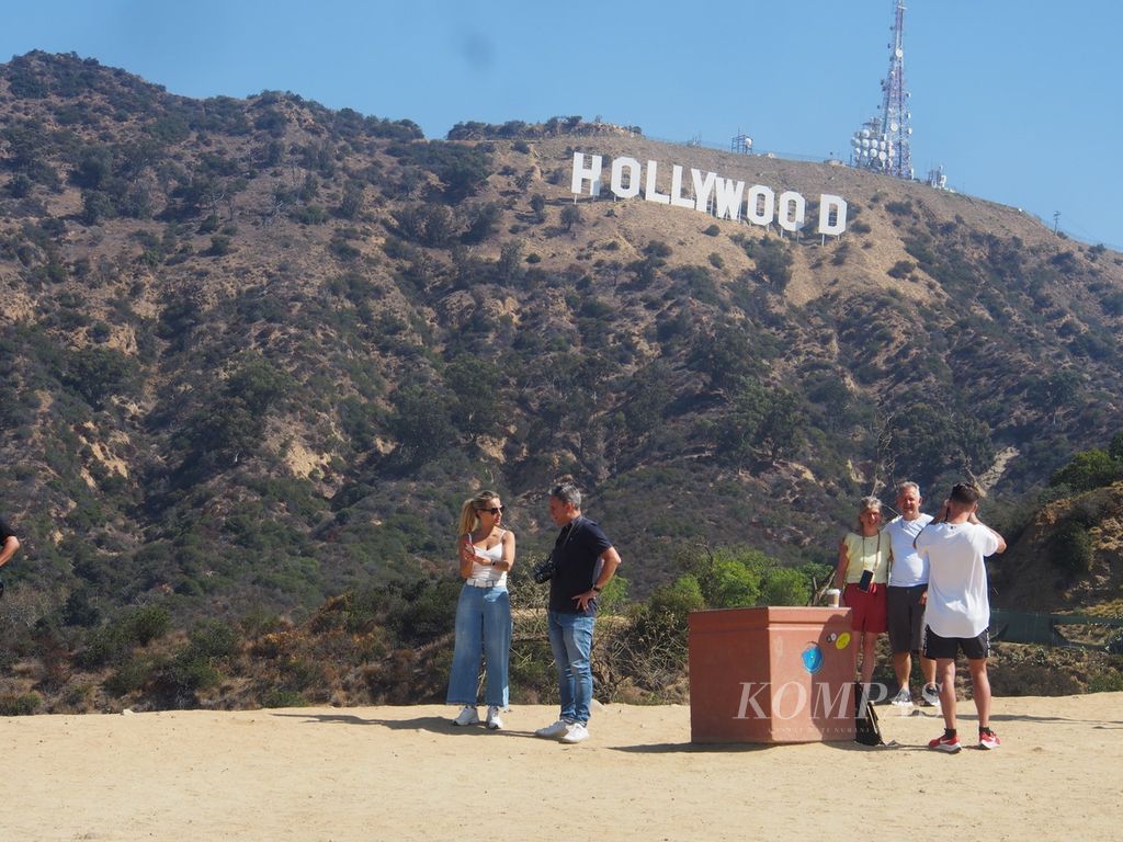 Sejumlah wisatawan mengabadikan momen saat berada di Hollywood Hills, Pegunungan Santa Monica, California, Amerika Serikat, dengan latar belakang markah Hollywood yang terkenal, Senin (29/8/2022). 