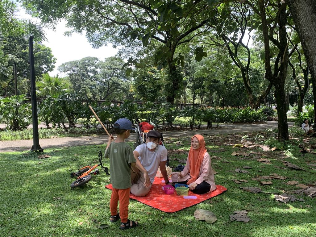 Arris dan Alia bercengkerama dengan anak laki-lakinya yang berusia empat tahun di Taman Hutan Kota Gelora Bung Karno, Senayan, Jakarta, Minggu (23/10/2022). Mereka berpiknik di kawasan olahraga itu sebanyak tiga kali dalam sebulan.
