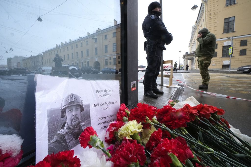 Karangan bunga dan poster dengan foto blogger, Vladlen Tatarsky, diletakkan dekat lokasi ledakan bom kafe "Street Bar" di St. Petersburg, Rusia, Senin (3/4/2023). (AP Photo/Dmitri Lovetsky)