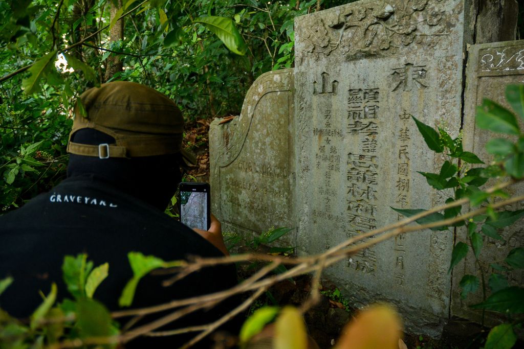 Anggota Indonesia Graveyard memotret nisan makam tradisional China (bongpay) di Semarang, Jawa Tengah pada Desember 2022. Makam yang tersembunyi di dalam hutan itu tertulis Pippo Agosto.