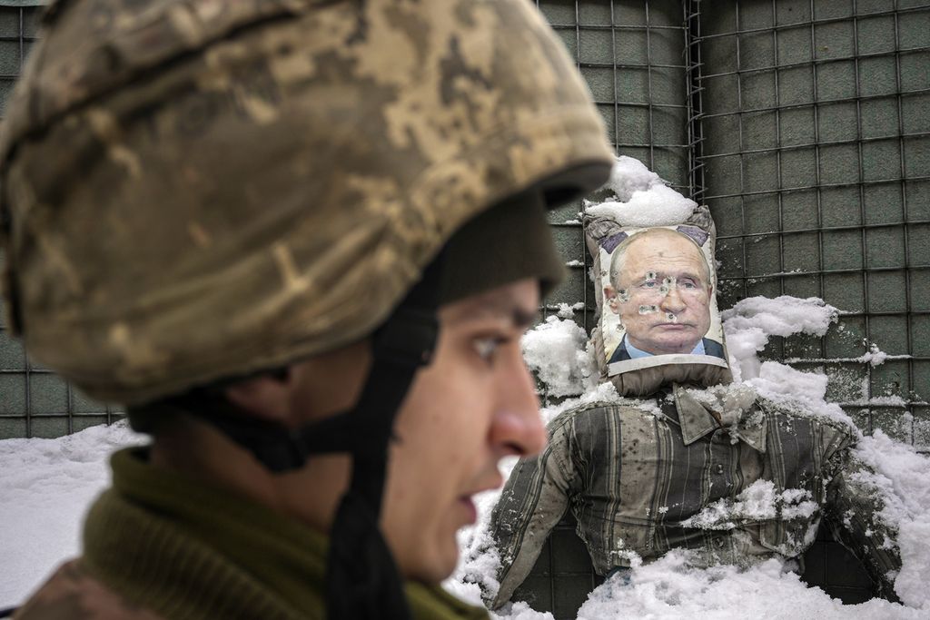 A Ukrainian serviceman speaks, backdropped by a bullet riddled effigy of Russian President Vladimir Putin, during a media interview at a frontline position in the Luhansk region, eastern Ukraine, Tuesday, Feb. 1, 2022. Russia accused the West of 