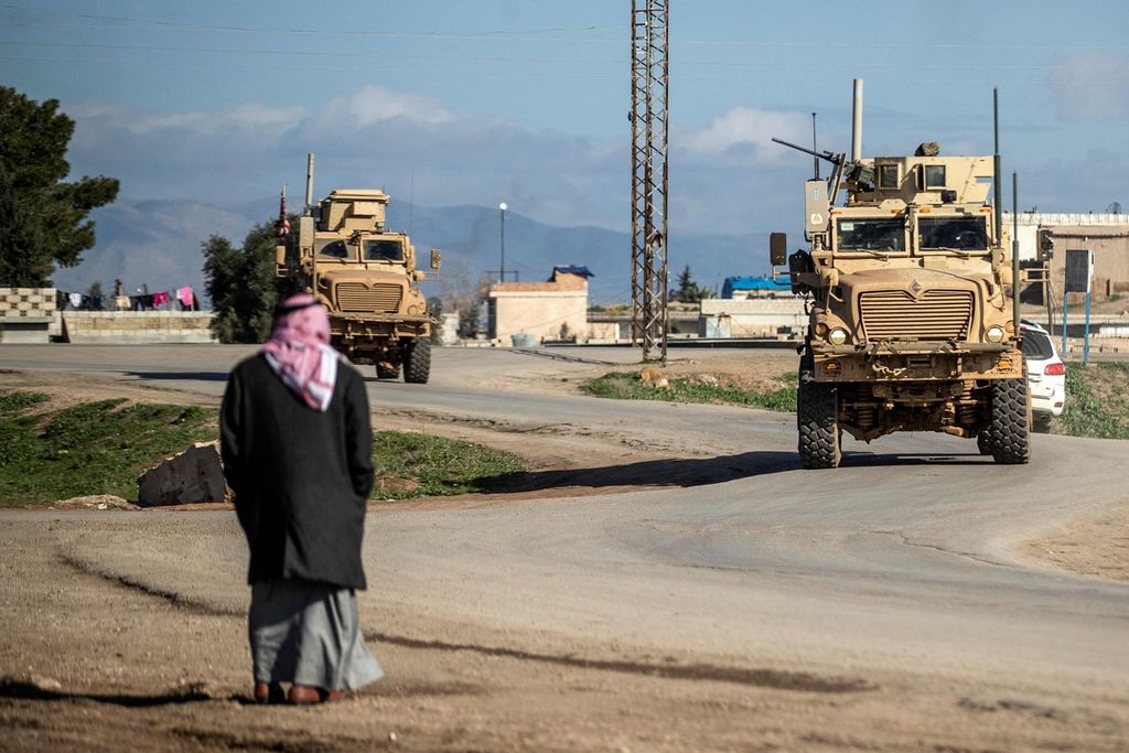 Seorang warga melihat kendaraan-kendaraan angkut lapis baja (APC) Amerika Serikat saat pasukan AS berpatroli di kota Tal Hamis, tenggara kota Qameshli, Hasakeh, Suriah timur laut, Rabu (24/1/2024). 
