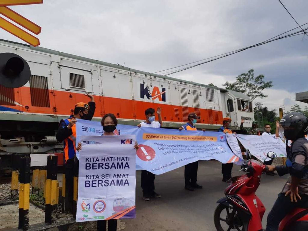 Petugas dan komunitas pencinta kereta api membawa spanduk menyerukan keselamatan berkendara di pelintasan sebidang di Jalan Veteran, Purwokerto Barat, Banyumas, Jawa Tengah, Senin (7/12/2020).