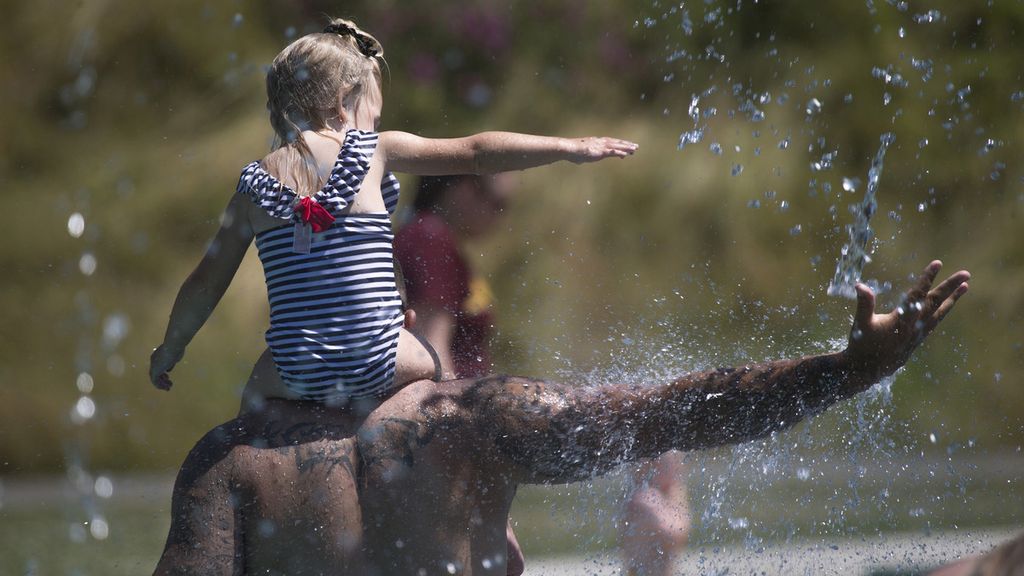 Beau Jess dan River (3), putrinya, bermain sembari mendinginkan diri di Taman Haller, Arlington, Washington, Amerika Serikat, saat cuaca panas, Senin (28/6/2021).