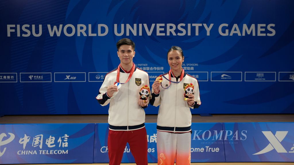 Atlet wushu Indonesia, Nandhira Mauriskha (kanan) dan Edgar Xavier Marvelo, menunjukkan medali yang diraihnya di Chengbei Gymnasium, Chengdu, China, Sabtu (29/7/2023) petang. Dalam gelaran Universiade itu, Nandhira mendapat medali emas dan Edgar meraih medali perak.