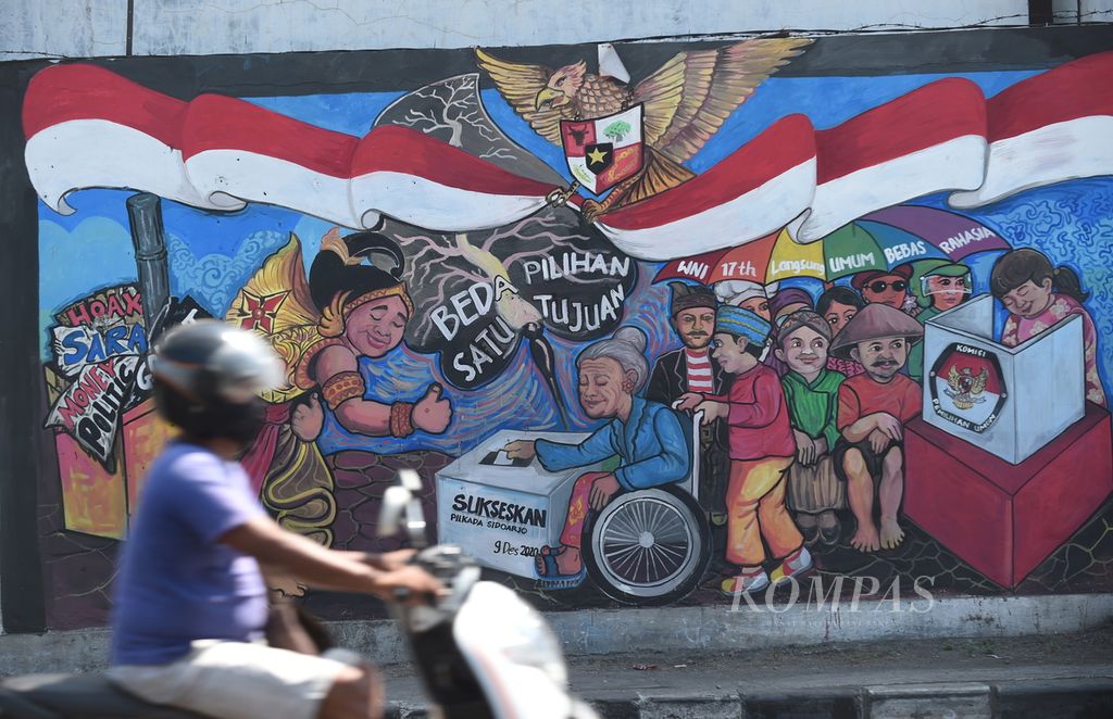 Warga melewati mural bertema pilkada di Jalan Lingkar Barat, Kecamatan Candi, Kabupaten Sidoarjo, Jawa Timur, Selasa (15/9/2020). Kampanye ajakan untuk berpartisipasi dalam pilkada yang bermartabat dipilih oleh KPU Sidoarjo melalui mural di sejumlah lokasi. 