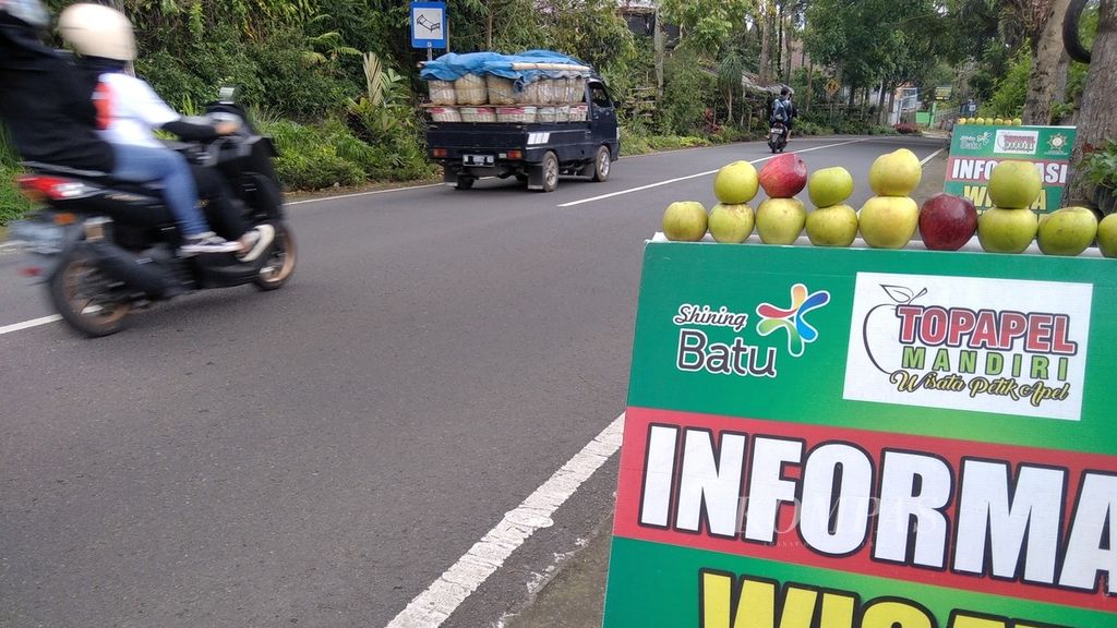 Pengendara melintasi pos informasi wisata petik apel yang berada di jalan raya Desa Tulungrejo, Kecamatan Bumiaji, Kota Batu, Jawa Timur, Kamis (3/3/2022).