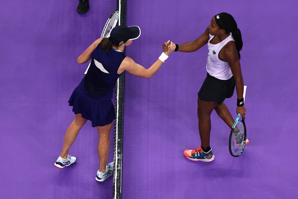 Petenis Polandia Iga Swiatek (kiri) bersalaman dengan petenis AS Coco Gauff pada laga penyisihan grup Turnamen Tenis WTA Finals di Fort Worth, Texas, Sabtu (5/11/2022). Swiatek memenangi laga itu.