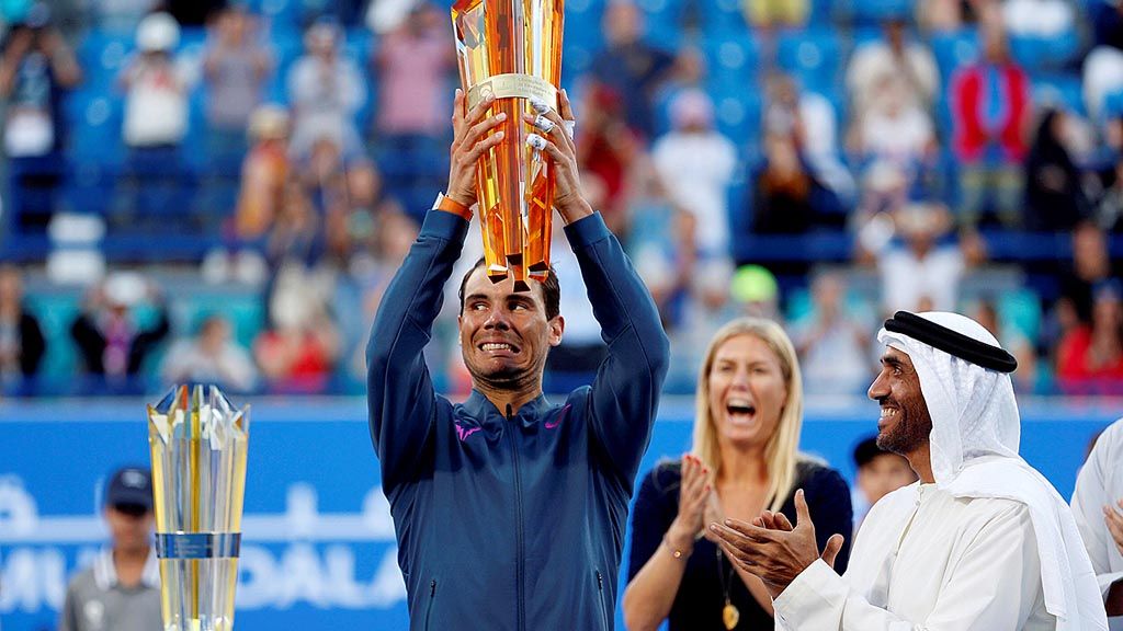 Petenis Spanyol Rafael Nadal   mengangkat trofi Kejuaraan Tenis Dunia Mubadala, seusai mengalahkan David Goffin (Belgia), di Abu Dhabi, Uni Emirat Arab, Sabtu (31/12). Nadal menerima trofi itu dari Direktur Dewan Olahraga Abu Dhabi Sheikh Nahyan bin Zayed Al Nahyan (kanan).