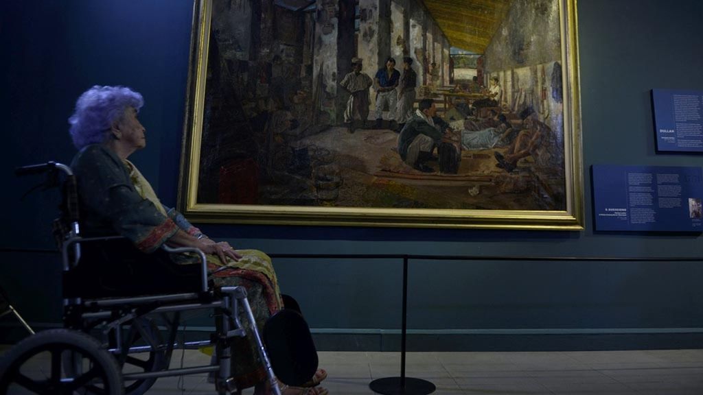 Rose Pandanwangi Sudjojono, istri pelukis Sudjojono, mengamati lukisan berjudul Markas Laskar di Bekas Gudang Beras Tjikampek karya suaminya yang dipamerkan dalam pameran koleksi seni rupa Istana Kepresidenan Republik Indonesia.