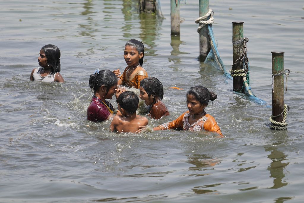 Anak-anak di India mendinginkan tubuh dengan berendam di Sungai Gomati saat daerah mereka di India bagian utara terus didera gelombang panas, Rabu (19/4/2023).