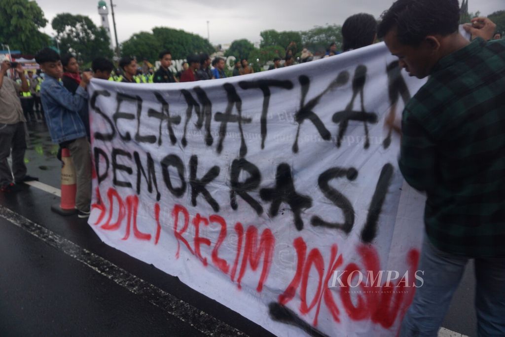 Mahasiswa berdemonstrasi sambil membawa spanduk besar, di Alun-alun Purwokerto, Banyumas, Jawa Tengah, Senin (19/2/2024).