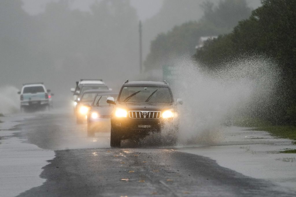Mobil-mobil melintasi banjir di Richmond, pinggiran Sydney, Australia, 4 Juli 2022. Lebih dari 30.000 penduduk Sydney dan sekitarnya dievakuasi akibat banjir. 