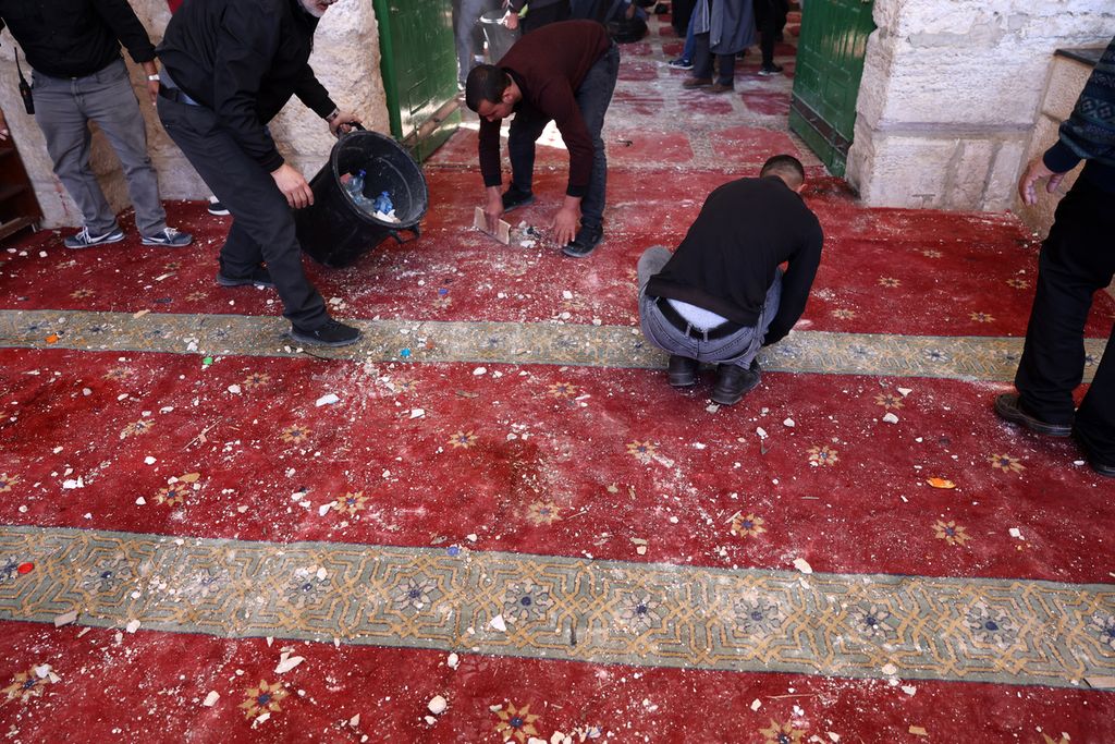Umat Muslim Palestina membersihkan puing dan kotoran yang ada di atas karpet di dalam ruangan Masjid Al-Aqsa, Jerusalem, Jumat (15/4), seusai bentrok dengan polisi Israel. 