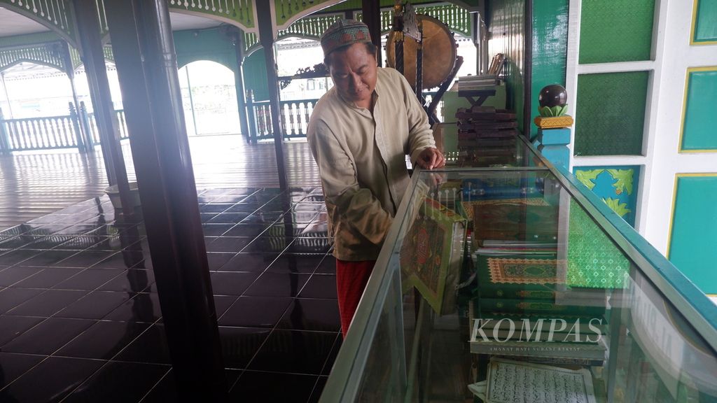 Zainuddin (42), marbot masjid, merapikan susunan kitab bacaan jemaah di Masjid Bersejarah Sultan Suriansyah, Banjarmasin, Kalimantan Selatan (18/3/2024).
