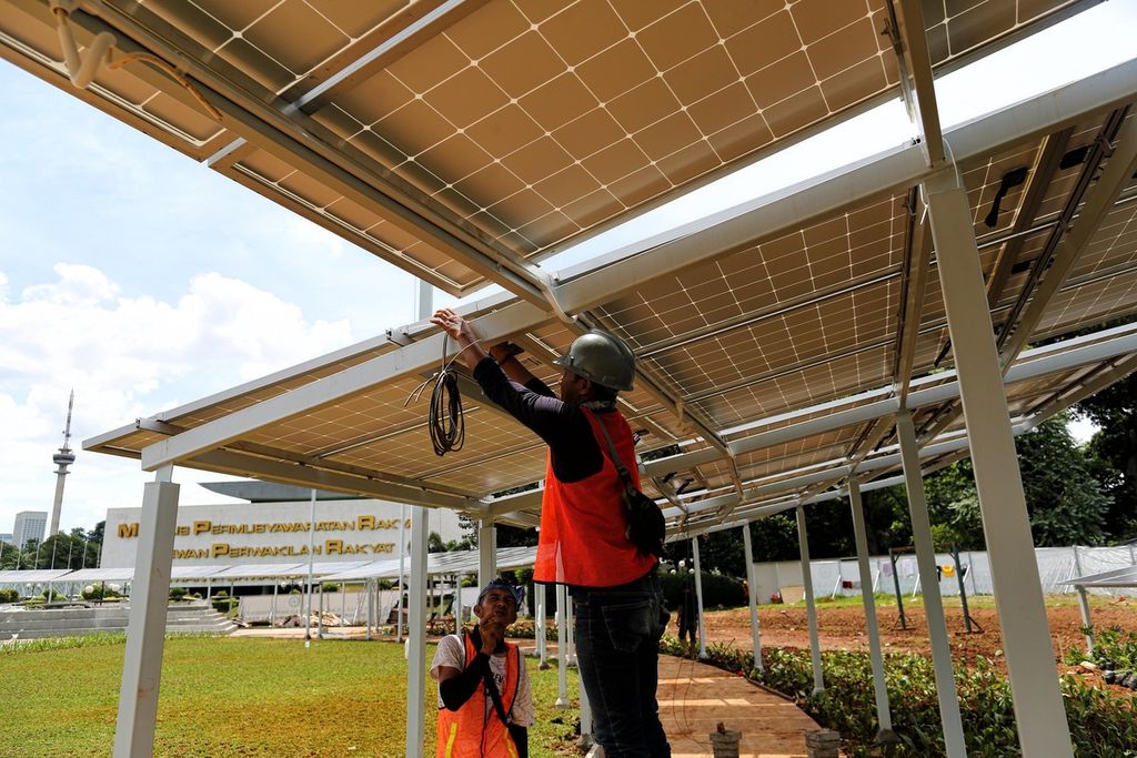 Pekerja menyelesaikan pemasangan panel surya di halaman kompleks Parlemen, Jakarta, 13 Desember 2021. 