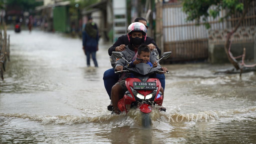 A motorcyclist penetrate the flood that submerged a village road in Kampung Pengarengan, Sukadaya Village, Sukawangi District, Bekasi Regency, West Java, Friday (3/3/2023).