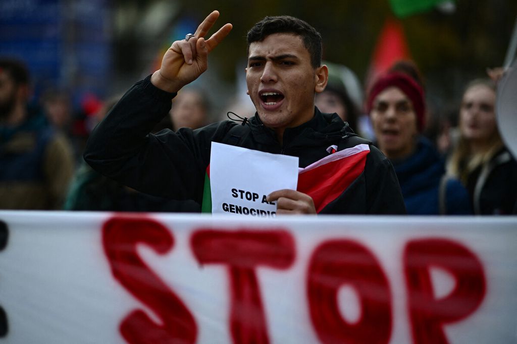 Seorang pengunjuk rasa memegang poster bertuliskan "hentikan genosida di Gaza" dalam aksi protes mendukung warga Palestina di Milan, Italia, Sabtu (4/11/2023).