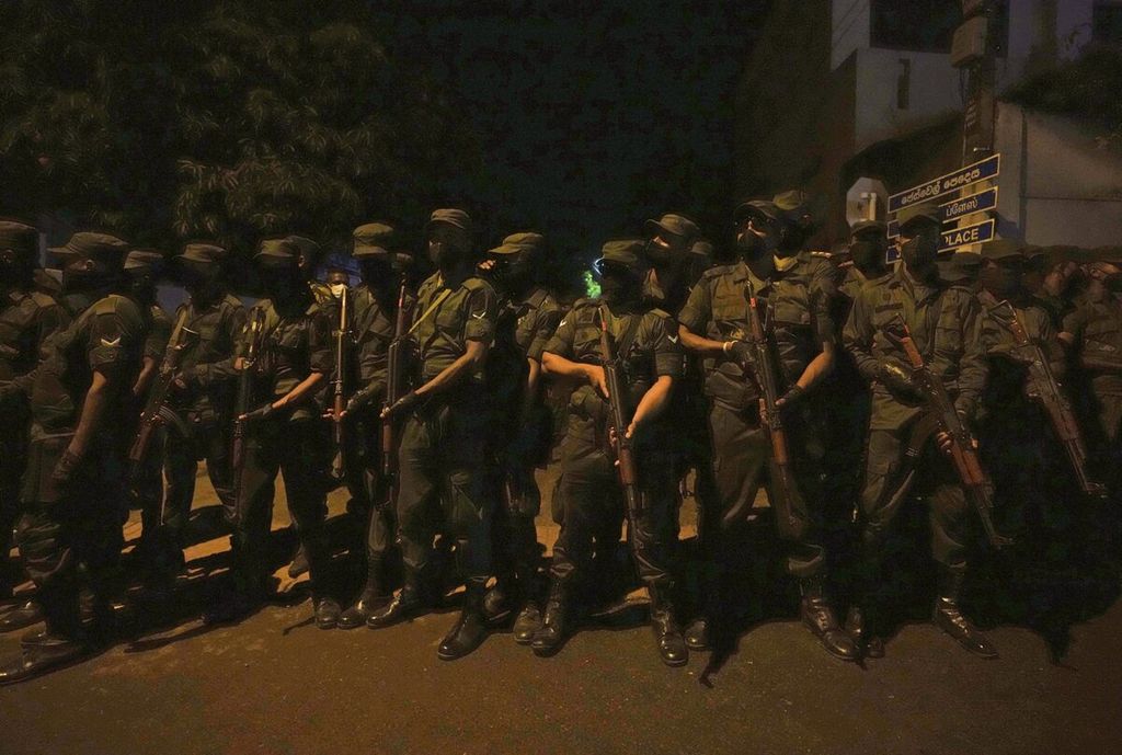 Tentara bersenjatakan senapan serbu disiagakan di dekat lokasi unjuk rasa pada Jumat (1/4/2022). Pasukan keamanan juga menembaki kerumunan, meski belum terkonfirmasi apakah mereka menggunakan peluru tajam atau peluru karet, untuk membubarkan massa. Laporan resmi menyatakan Presiden Rajapaksa tidak berada di kediaman saat unjuk rasa berlangsung. 