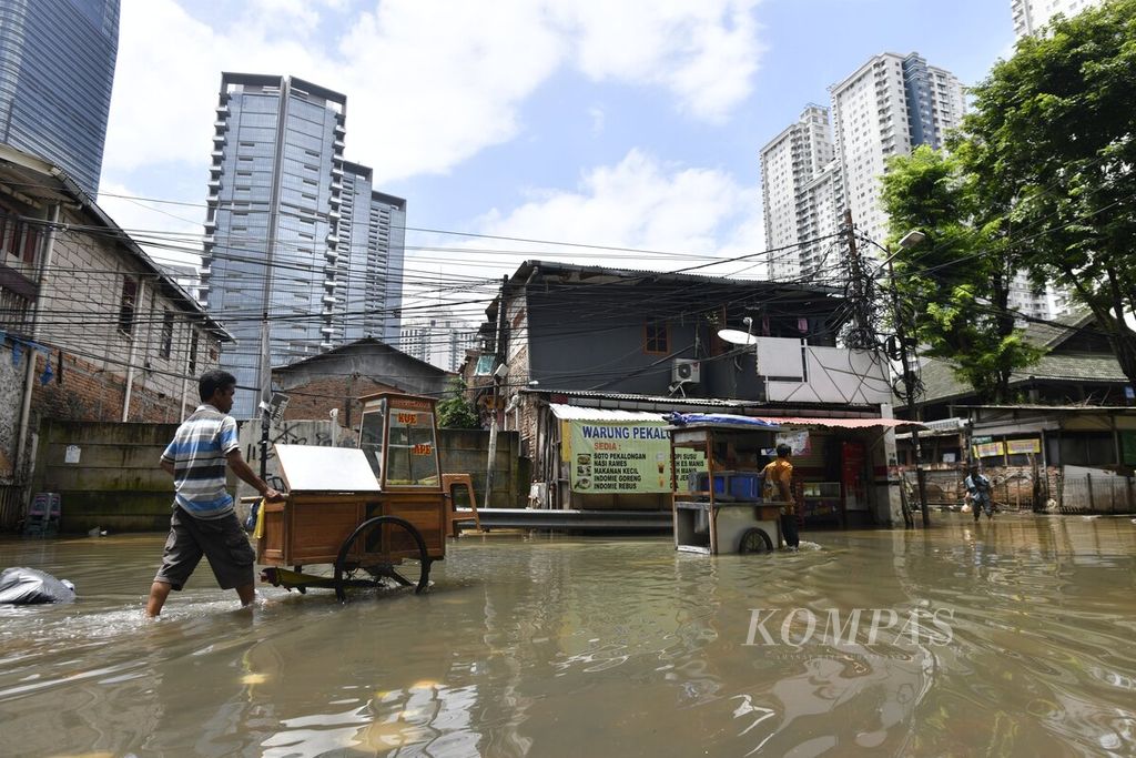 Penjual makanan mendorong gerobak melewati banjir di Jalan Karet Pasar Baru Timur, Tanah Abang, Jakarta Pusat, 23 Februari 2020. Peningkatan curah hujan secara ekstrem diperkirakan merupakan dampak dari perubahan iklim.