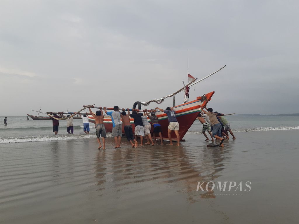 Nelayan yang bermukim di kampung nelayan tradisional Malabero, Kota Bengkulu, bergotong royong mendorong kapal yang hendak digunakan untuk melaut pada Rabu (15/11/2023) sore.