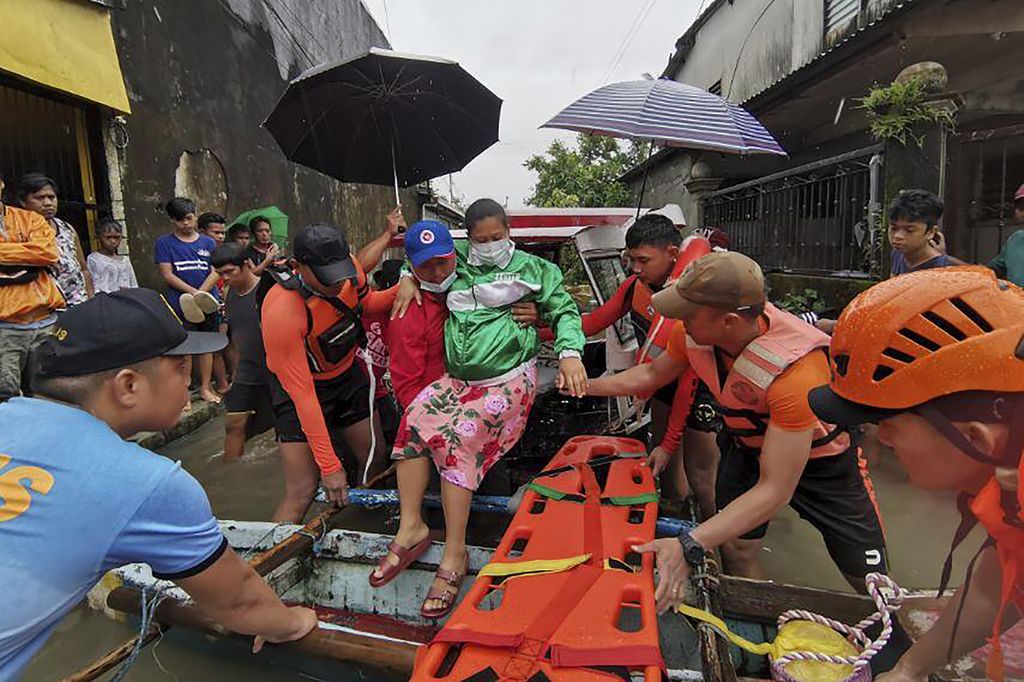 Petugas penyelamat mengevakuasi warga ke tempat yang lebih aman di Abuyog, Provinsi Leyte, Filipina, 10 April 2022. Hujan deras akibat badai tropis menewaskan puluhan orang yang terkena terjangan banjir dan tanah longsor. 