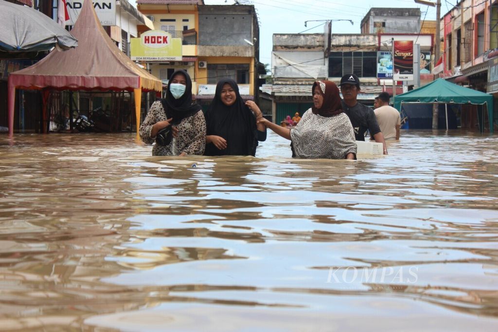 Warga menerobos banjir di pusat perdagangan di Kota Lhoksukon, Kabupaten, Aceh Utara, Aceh, Senin (3/1/2022). Mobil menerobos banjir di jalan nasional Banda Aceh–Medan, di Kota Lhosukon, Kabupaten Aceh Utara, Aceh, Senin (3/1/2022).  Kawasan Lhoksukon nyaris setiap tahun dilanda banjir. Intensitas hujan yang tinggi, kondisi daerah aliran sungai yang kritis, dan deforestasi memicu banjir semakin masif.