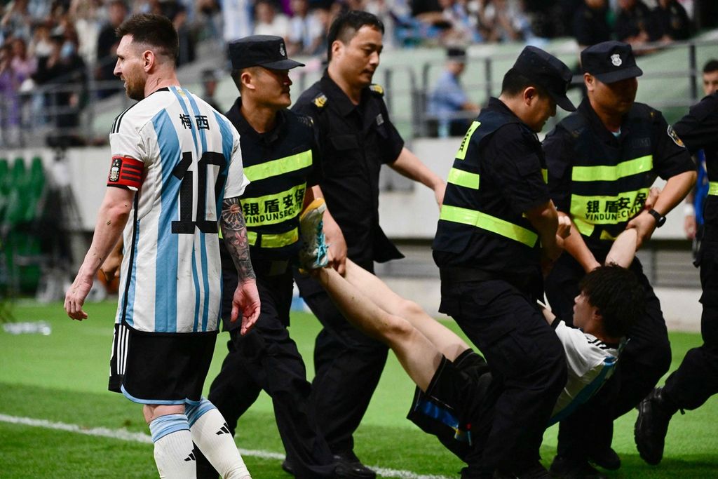 Petugas meringkus seorang penonton yang memasuki lapangan dalam pertandingan persahabatan antara Argentina dan Australia di Stadion Pekerja, Beijing, China, Kamis (15/6/2023).