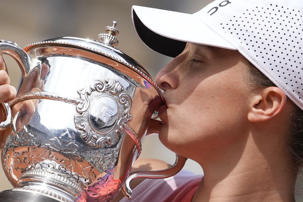 Iga Swiatek mencium trofi juara Perancis Terbuka seusai mengalahkan Jasmine Paolini pada pertandingan final di Roland Garros, Paris, Sabtu (8/6/2024).