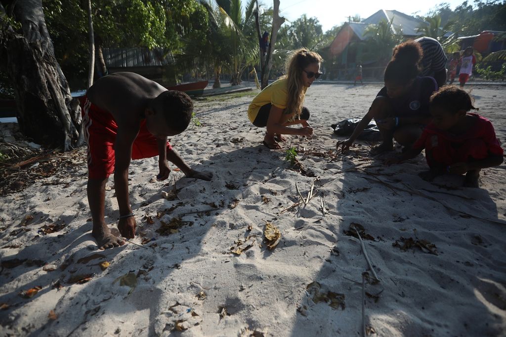 Sejumlah anak-anak bersama Kerry, guru bahasa Inggris di sekolah mereka, memungut sampah anorganik di pesisir Pantai Kampung Sawandarek, Pulau Mansuar, Distrik Meos Mansar, Kabupaten Raja Ampat. Papua Barat, Jumat (22/11/2019).