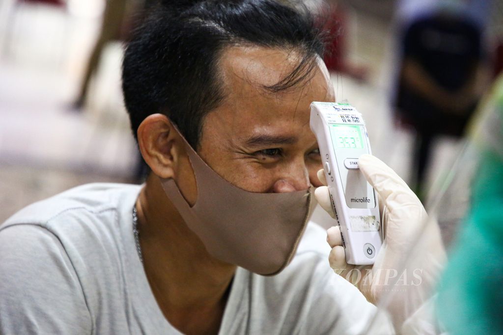 Pedagang di Pasar Tanah Abang Blok A, Jakarta Pusat menjalani pemeriksaan suhu tubuh sebelum menerima suntikan vaksin Covid-19 dosis pertama, Kamis (18/2/2021).