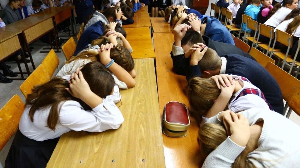 Anak-anak sekolah di Desa Sartana, Ukraina Timur, melindungi kepala dengan kedua tangan saat mereka mengikuti latihan perlindungan diri dari serangan atau peperangan. Sedikitnya 200.000 anak terpaksa belajar di sekolah yang terletak di daerah-daerah rawan konflik.