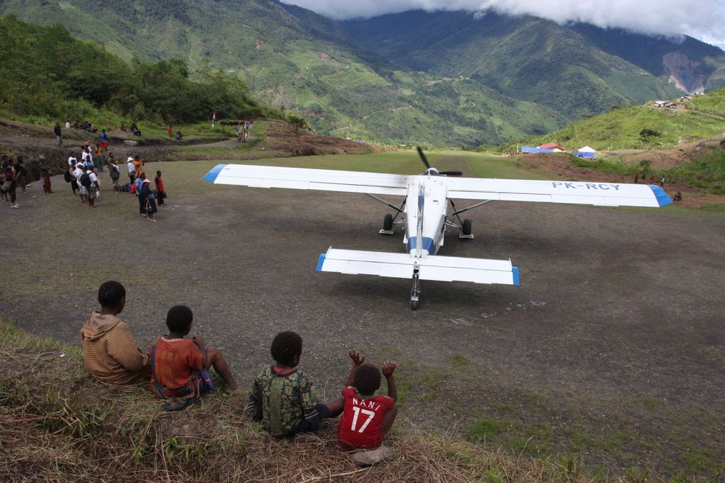 Anak-anak warga Distrik Oklip, Kabupaten Pegunungan Bintang, Papua, tengah menyaksikan pesawat perintis milik AMA, Selasa (13/12/2011). Pesawat-pesawat perintis seperti itulah yang menjadi penghubung wilayah pedalaman Papua.