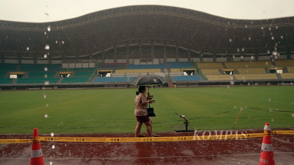 Warga lansia menembus hujan deras setelah menjalani vaksinasi penguat di gerai vaksin presisi di Stadion Patriot Candrabhaga, Kota Bekasi, Jawa Barat, Selasa (8/2/2022). 
