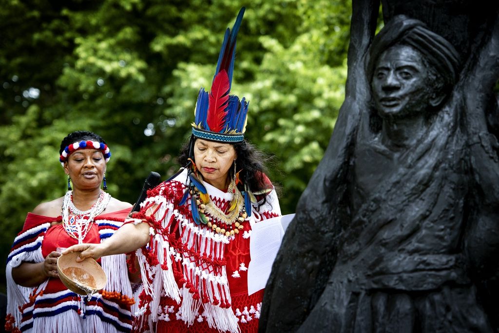 Seorang perempuan menuangkan persembahan pada peringatan Hari Kesadaran, Festival KetiKoti, perayaan penghapusan perbudakan, di Amsterdam, Belanda, Sabtu (1/7/2023). 